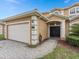 Beige two-story home featuring an attached two-car garage and manicured landscaping at 426 Vista Loop, Davenport, FL 33897