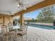 Relaxing outdoor patio featuring a pool, outdoor kitchen, and glass table with metal chairs at 426 Vista Loop, Davenport, FL 33897