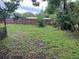 A spacious backyard featuring grass, trees, and a wooden fence at 5123 Turnbull Dr, Orlando, FL 32812