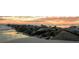 Scenic beach view featuring a rock barrier stretching into the ocean with a gorgeous sunset sky at 5300 S Atlantic Ave # 6-502, New Smyrna Beach, FL 32169