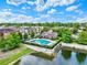 Aerial view of the neighborhood pool area surrounded by lush greenery and a serene pond at 5464 Factors Walk Dr, Sanford, FL 32771