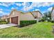 A wide view of the attached garage and lawn showing manicured shrubs and a green lawn at 5464 Factors Walk Dr, Sanford, FL 32771