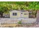 Charming yellow cottage-style home with a white picket fence and lush green trees at 5750 Delta St, Orlando, FL 32807