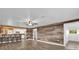 Open-concept living room with a rustic wood accent wall, a kitchen bar, and modern flooring at 5750 Delta St, Orlando, FL 32807
