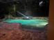 Beautiful screened pool featuring a rock waterfall, spa, and landscape lighting at 626 Green Rock Ct, Apopka, FL 32712