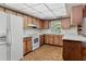 Kitchen features wood cabinets, white appliances, brick floors, and white countertops at 6411 Merriewood Dr, Orlando, FL 32818