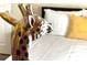 Close-up of a giraffe statue next to a bed with white linens and a yellow decorative pillow in a bedroom at 8101 Resort Village Dr # 31501, Orlando, FL 32821