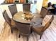 Dining area with a round glass table and six wicker chairs on wood flooring at 8101 Resort Village Dr # 31501, Orlando, FL 32821