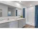 Modern bathroom featuring a double vanity, large mirror, and a walk-in shower with blue accents at 1028 Morfontaine St, Daytona Beach, FL 32124
