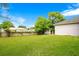 Green backyard with lawn and some perimeter shrubbery with a partial view of the building on the right at 1116 Adirondack St, Deltona, FL 32725