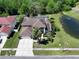 Beautiful aerial view of a brown roof home next to a pond with solar panels and pool in the fenced-in backyard at 12618 Greco Dr, Orlando, FL 32824