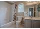 Bright bathroom with shower-tub combo, toilet, large mirror and a window for natural light at 12618 Greco Dr, Orlando, FL 32824