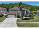Stunning two-story home featuring a well-manicured lawn, mature palm trees, and a spacious driveway leading to a two-car garage at 12618 Greco Dr, Orlando, FL 32824