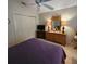 A well-lit bedroom featuring a ceiling fan, dresser with mirror, television and closet at 16922 Se 81St Charlesfort Ave, The Villages, FL 32162