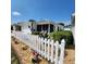 Home exterior featuring a charming screened-in lanai area, and a neatly maintained yard with a white picket fence at 16922 Se 81St Charlesfort Ave, The Villages, FL 32162
