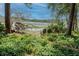 A serene backyard vista of the lake with two Adirondack chairs amidst a lush forest, ideal for peaceful contemplation at 1778 Waterside Oaks Dr, Orange City, FL 32763