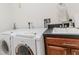 Close-up of a modern washer and dryer with dark countertops and wooden cabinets at 1778 Waterside Oaks Dr, Orange City, FL 32763
