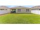Spacious backyard with a well-manicured lawn, covered patio, and white vinyl fence at 1975 Cacutta Way, Kissimmee, FL 34744