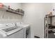 Convenient laundry room features a washer, dryer, and wire shelving for storage at 1975 Cacutta Way, Kissimmee, FL 34744