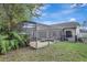 Backyard featuring a screened-in pool, lush landscaping, and a view of the home's exterior at 2019 Wintermere Pointe Dr, Winter Garden, FL 34787