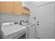 A clean laundry room features a washer, dryer, and overhead cabinets for storage at 2217 Caledonian St, Clermont, FL 34711