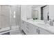 Bright bathroom featuring double vanity, white cabinetry, and glass-enclosed shower, creating a clean aesthetic at 300 Muirfield Loop, Reunion, FL 34747