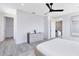 A minimalist bedroom has a modern dresser, ceiling fan, and two entryways with clean lines and neutral tones at 300 Muirfield Loop, Reunion, FL 34747