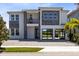Modern two-story home featuring a stone facade, balcony with hanging chair, and a glass paneled two-car garage at 300 Muirfield Loop, Reunion, FL 34747