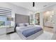 Bright main bedroom with large grey tufted headboard, ensuite bath, and large windows at 300 Muirfield Loop, Reunion, FL 34747