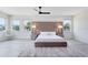 Serene main bedroom with a tufted headboard, ambient lighting, and hardwood floors, accentuated by natural light from large windows at 300 Muirfield Loop, Reunion, FL 34747