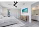Serene main bedroom featuring hardwood floors, a mirrored dresser, a TV, and a view to the en suite bathroom at 300 Muirfield Loop, Reunion, FL 34747