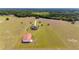 Aerial view featuring a home, a barn, and fenced pastures with mature trees, offering a serene country lifestyle at 35651 Huff Rd, Eustis, FL 32736