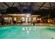 A glowing in-ground pool is lit up at night with a covered patio and outdoor seating area at 502 Oak Ln, Maitland, FL 32751