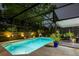 Nighttime view of a sparkling in-ground pool with an enclosed screen and outdoor seating area at 502 Oak Ln, Maitland, FL 32751