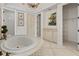 Luxury bathroom featuring a tiled tub with chandelier, with views to a closet and decorative cabinet at 5909 Oxford Moor Blvd, Windermere, FL 34786