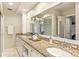 Bright bathroom featuring double sinks, granite countertops, white cabinets, a large mirror and an orchid at 627 Darcey Dr, Winter Park, FL 32792