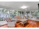 Bright sunroom with tile flooring, surrounded by large windows offering lush outdoor views and comfortable wicker furniture at 627 Darcey Dr, Winter Park, FL 32792