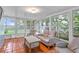Bright sunroom with tile flooring, surrounded by large windows offering lush outdoor views and comfortable wicker furniture at 627 Darcey Dr, Winter Park, FL 32792