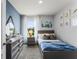 Bedroom with coastal decor, gray dresser, and a cozy bed with coordinated blue bedding at 7173 Cow Prairie Rd, St Cloud, FL 34773