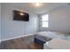 This bedroom has a mounted TV, white trim, a window letting in natural light, and wood-look flooring at 719 Tortugas St, Haines City, FL 33844