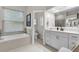 Bright bathroom featuring a soaking tub under a window, vanity with white cabinets, and tiled floors at 7288 Winding Lake Cir, Oviedo, FL 32765
