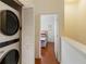 Hallway laundry closet features stackable washer and dryer, with view of bedroom with hardwood floor at 7663 Fitzclarence St, Kissimmee, FL 34747