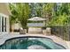 Backyard pool with outdoor seating, lush landscaping, white fencing, and an umbrella at 9534 Piccadilly Sky Way, Orlando, FL 32827
