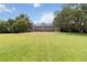 Large grassy backyard with mature oak trees and a screened-in pool enclosure visible in the distance at 1093 Hidden Harbor Ln, Kissimmee, FL 34746