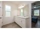 Bright bathroom featuring double sinks, white cabinets, and a large mirror at 1167 Celery Oaks Ln, Sanford, FL 32771