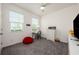 A cozy carpeted bedroom with two windows, a desk, and a cheerful red beanbag at 1167 Celery Oaks Ln, Sanford, FL 32771