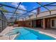 View of the pool, spa and brick patio within the screened-in enclosure at 12202 Rambling Oak Blvd, Orlando, FL 32832
