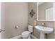 Modern powder room featuring a pedestal sink with gold faucet, illuminated mirror, and sleek toilet at 12289 Prairie Plantation Way, Orlando, FL 32824