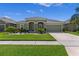 Charming single-story home featuring lush green lawn, colorful flower beds, and a driveway leading to a two-car garage at 12289 Prairie Plantation Way, Orlando, FL 32824