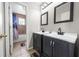 Bathroom with dual vanity, framed mirrors, tiled floors, and shower-tub combo at 1233 Nelson Park Court, Poinciana, FL 34759